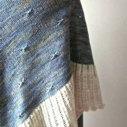 Closeup of a blue shawl with a cream edging.