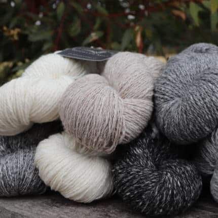Skeins of white, tan and gray yarn.