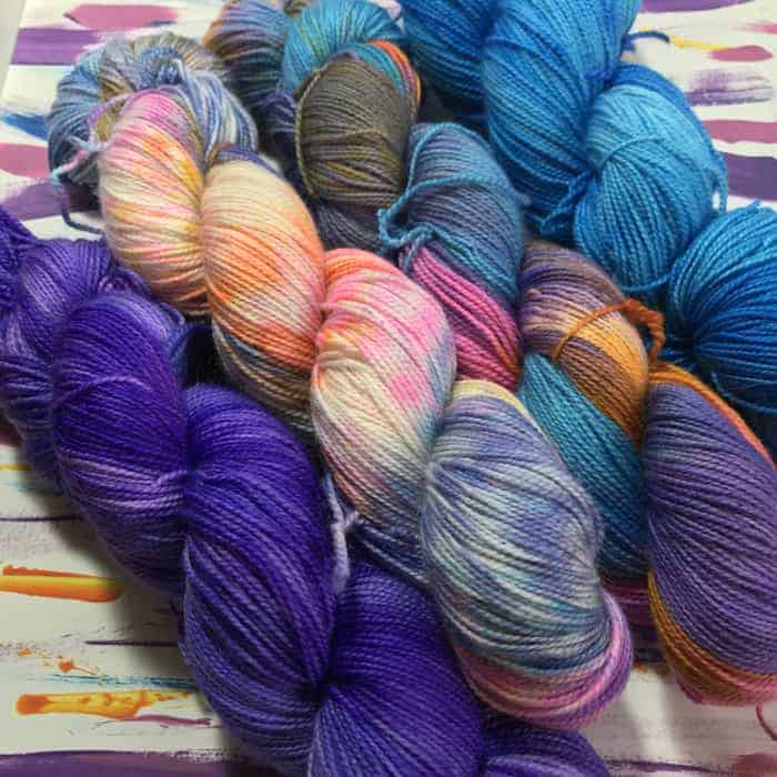 Four skeins of yarn in purple, blue, pink and orange variegated colorways. 