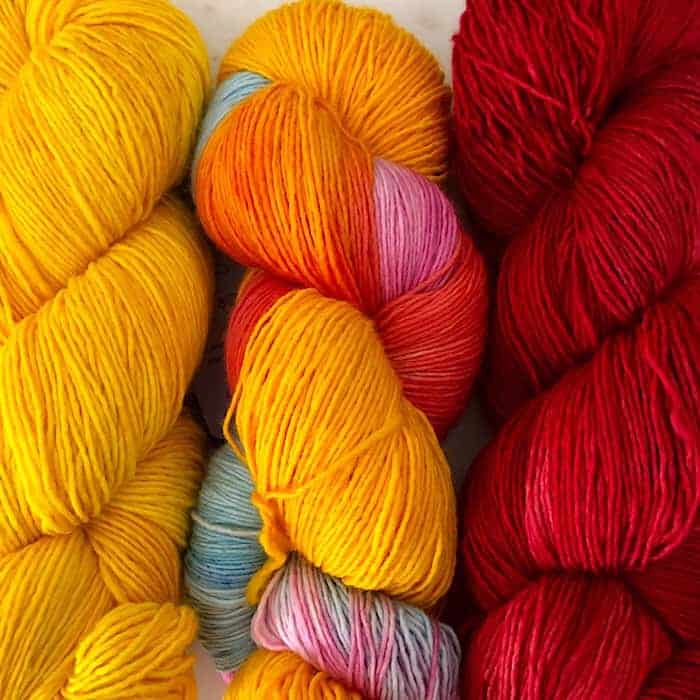 Yellow, yellow and pink variegated and red yarn.