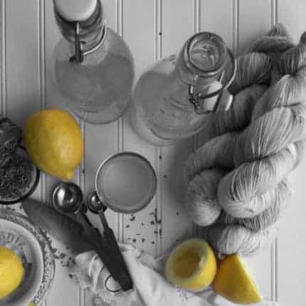 A black and white image of yarn on a table with yellow lemons.