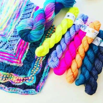 A set of fluorescent yellow, purple, pink, orange and teal yarn with a shawl using the same colors.