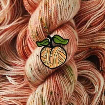 A peach pin over peach colored speckled yarn.