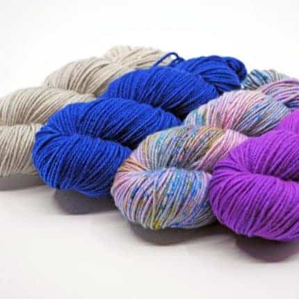 Hanks of grey, bright blue, variegated purple and blue and purple yarn.