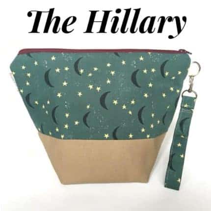 A zipper bag with a green and blue bird fabric with the text The Hillary.