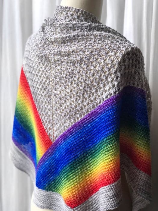 A lacy ivory shawl with a rainbow at the bottom