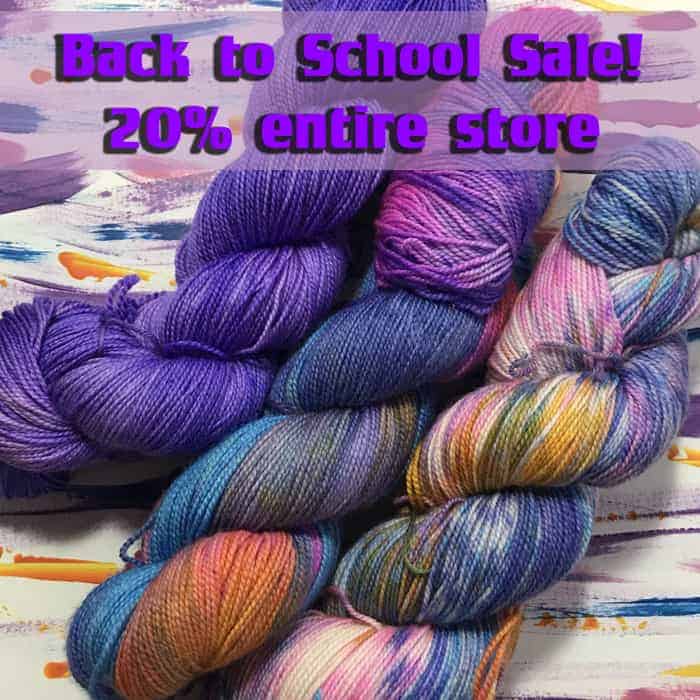 Skeins of solid purple and blue and orange and pink, blue and yellow variegated yuarn with the words Back to school sale, 20% off entire store