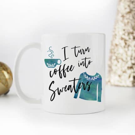 A white mug that reads, I turn coffee into sweaters with a teal sweater and cup of coffee pictured