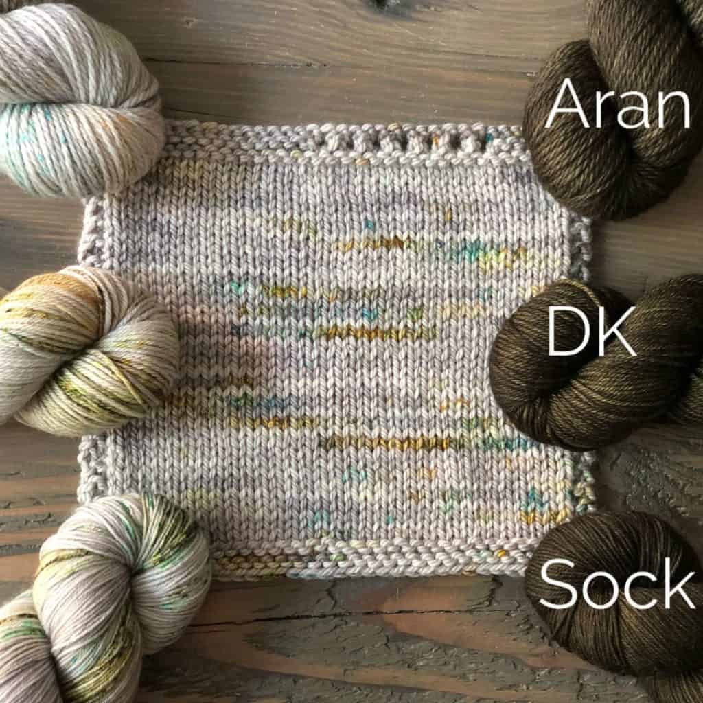 Gray yarn with gold and green speckles and olive green yarn labeled Aran, DK and Sock