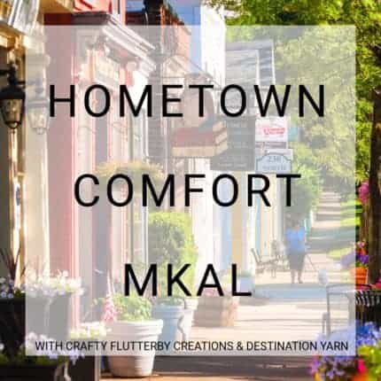 A picture of a downtown street and the words Hometown Comfort MKAL with Crafty Flutterby Creations and Destination Yarn