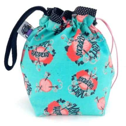 An aqua drawstring bag with pink yarn balls and the words Knit Happens.