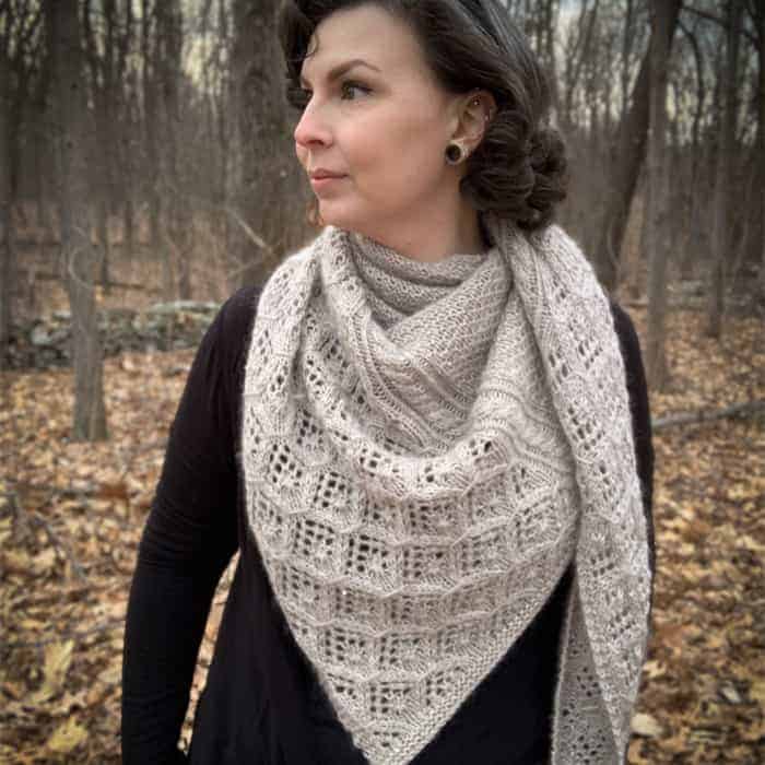 A woman models a thick, white, lacy shawl.