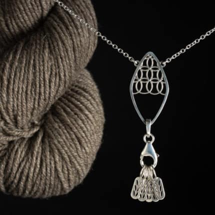 A skein of taupe yarn and a silver necklace.