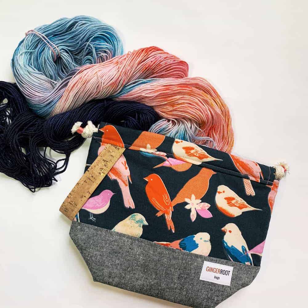 A bag with birds and red and blue yarn.