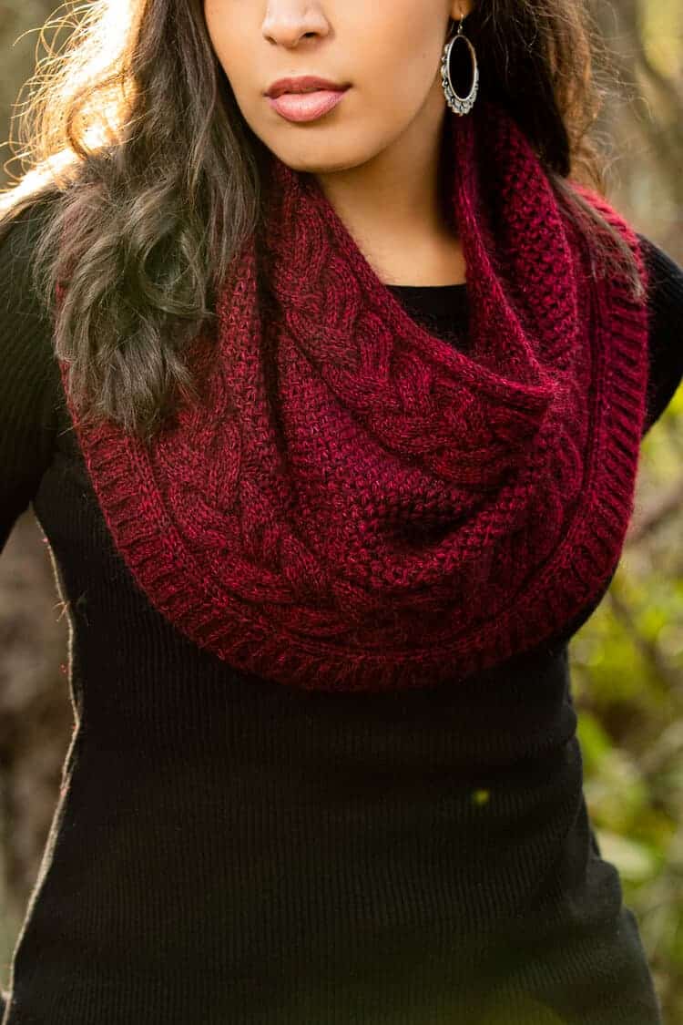 A woman models a red cabled cowl.