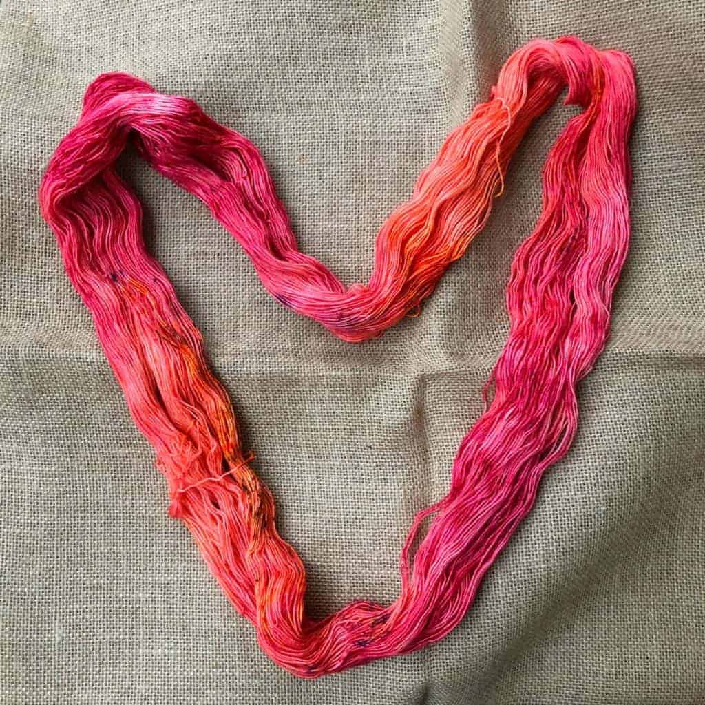 A pink and orange hank of yarn in the shape of a heart.