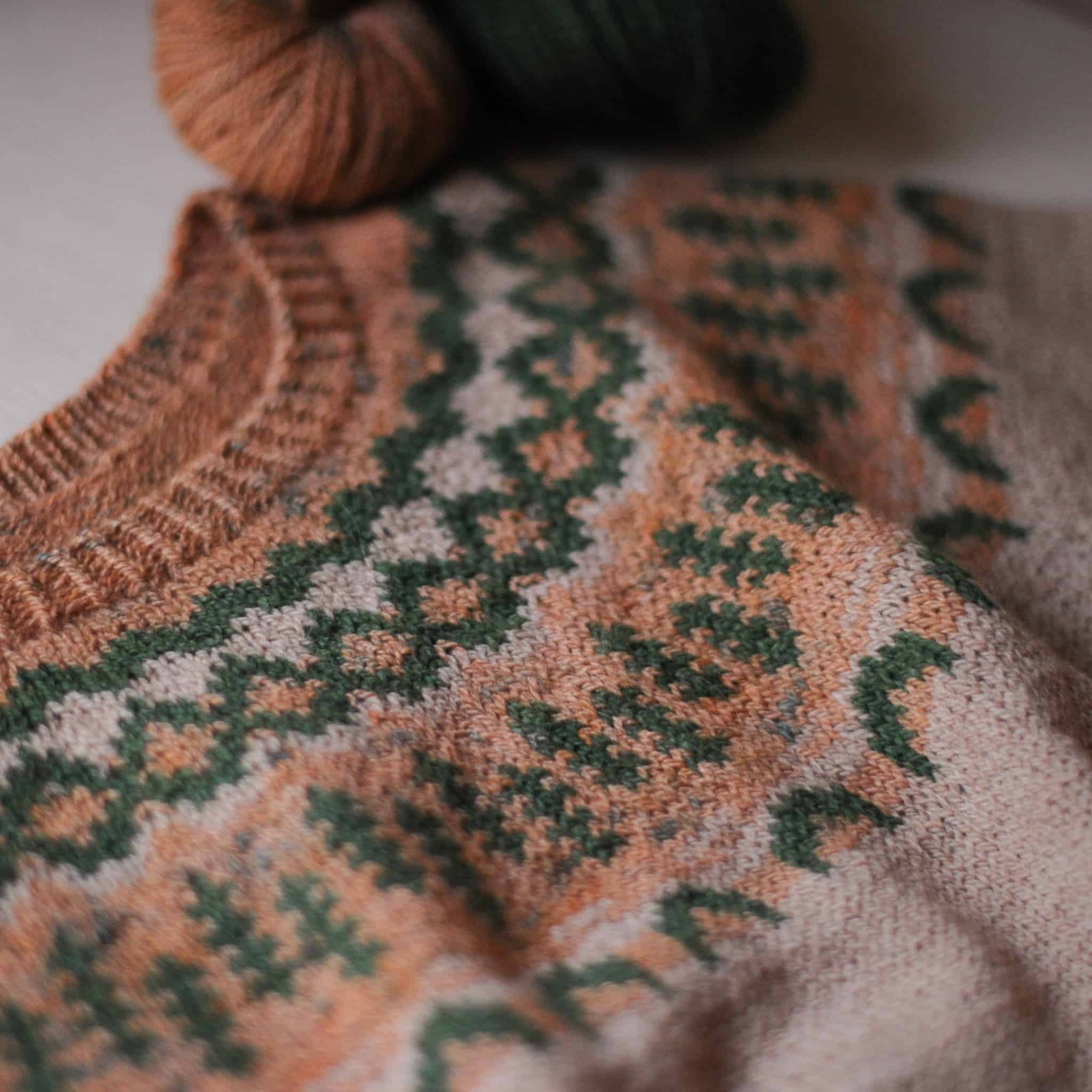 A peach and forest green colorwork yoke sweater.