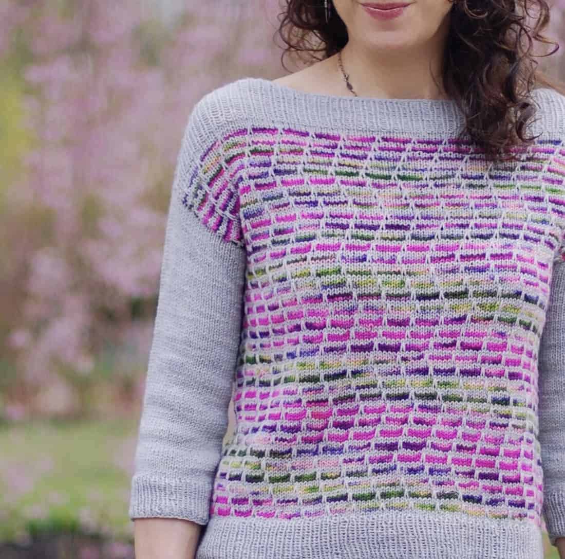 A grey pullover with a purple and green variegated front.