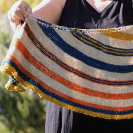 A cream-colored shawl with orange, navy and mustard stripes.