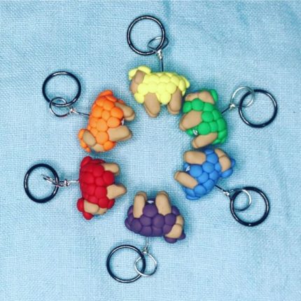 Clay sheep stitch markers in a rainbow of colors form a circle.