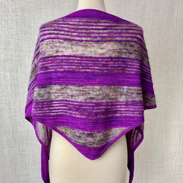 A purple and gray striped shawl sits on a dress form.
