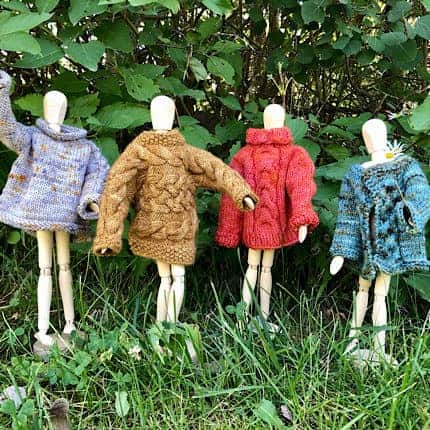 Mini mannequins wearing colorful mini sweaters.