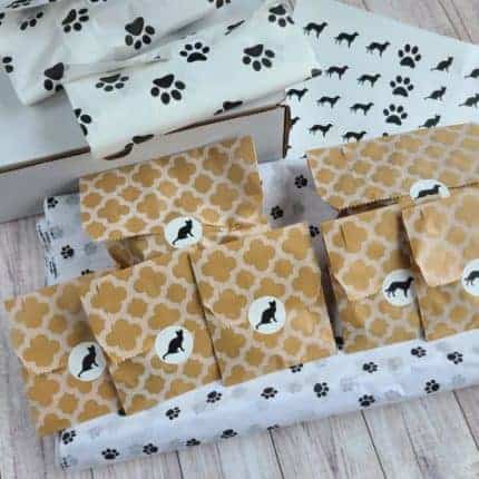 Packages with black and white cat stickers and dog paw tissue paper.
