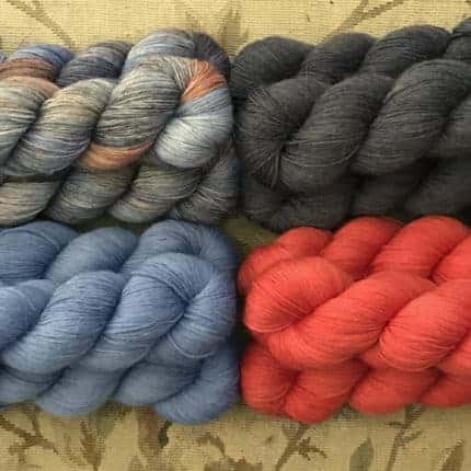 Skeins of gray, steel blue, dark green and tomato red yarn.