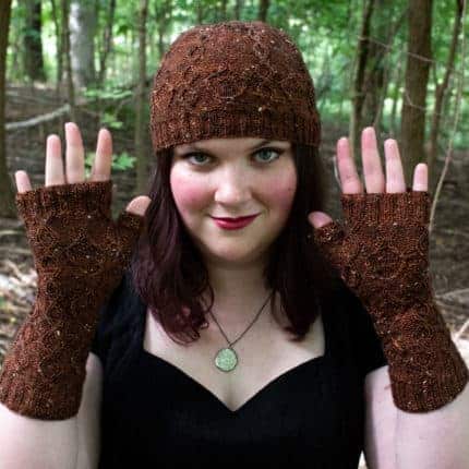 A woman models a brown cabled hat and mitts.