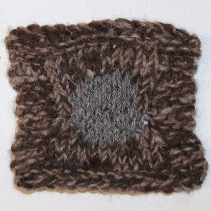 A brown knitted square with a circle of gray.
