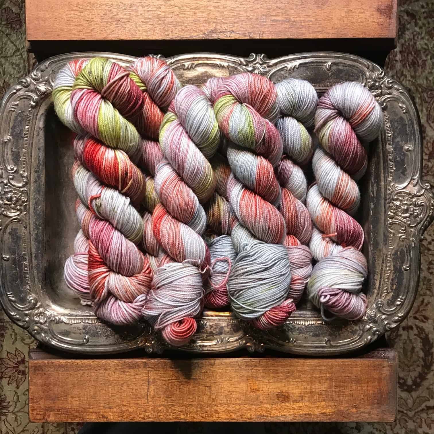 Yarn speckled with red, pink and green on a silver tray.