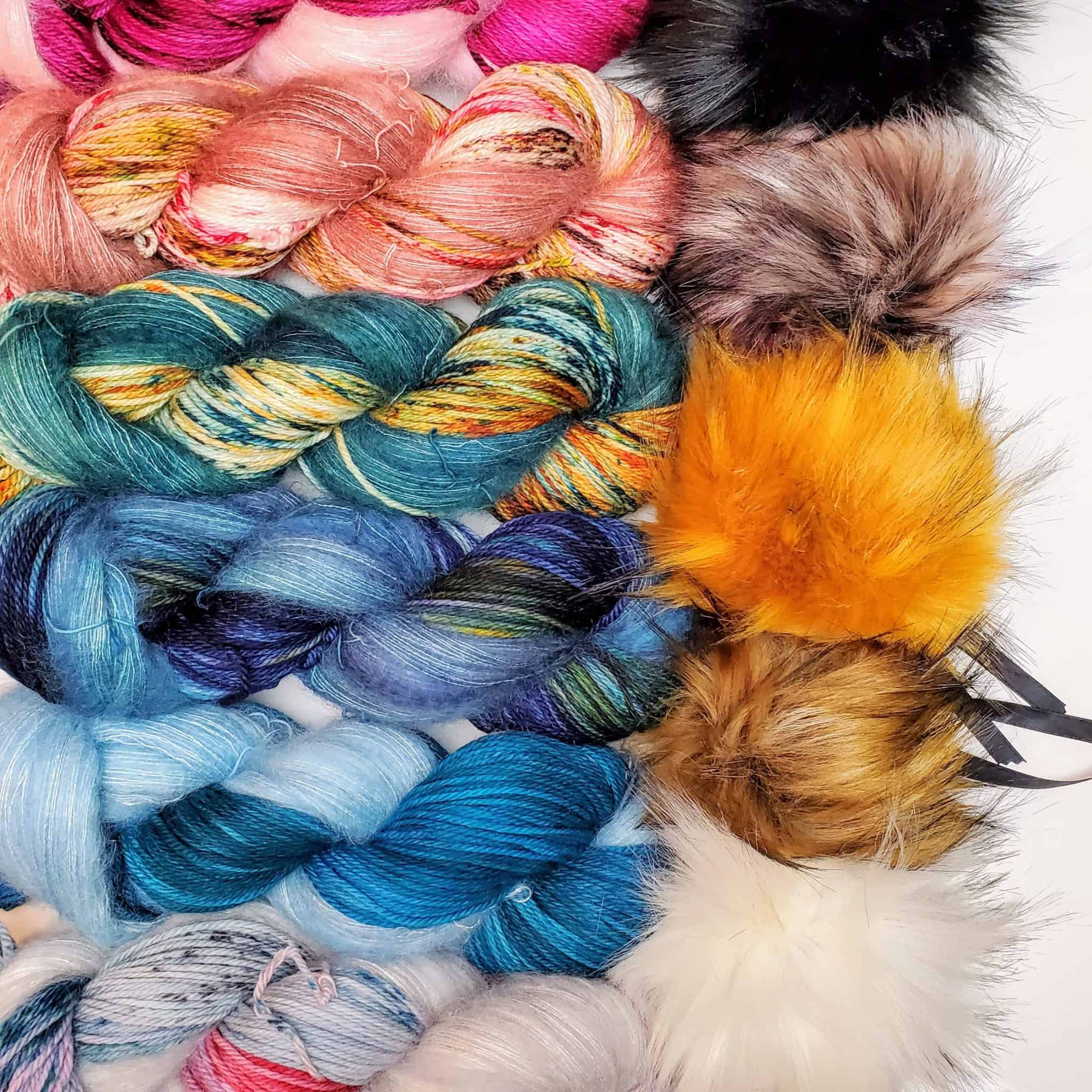Multicolored skeins of yarn and faux fur pom-poms.