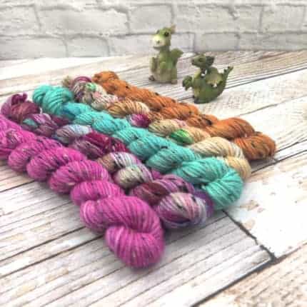 Skins of pink, purple speckled, green, beige and amber yarn.