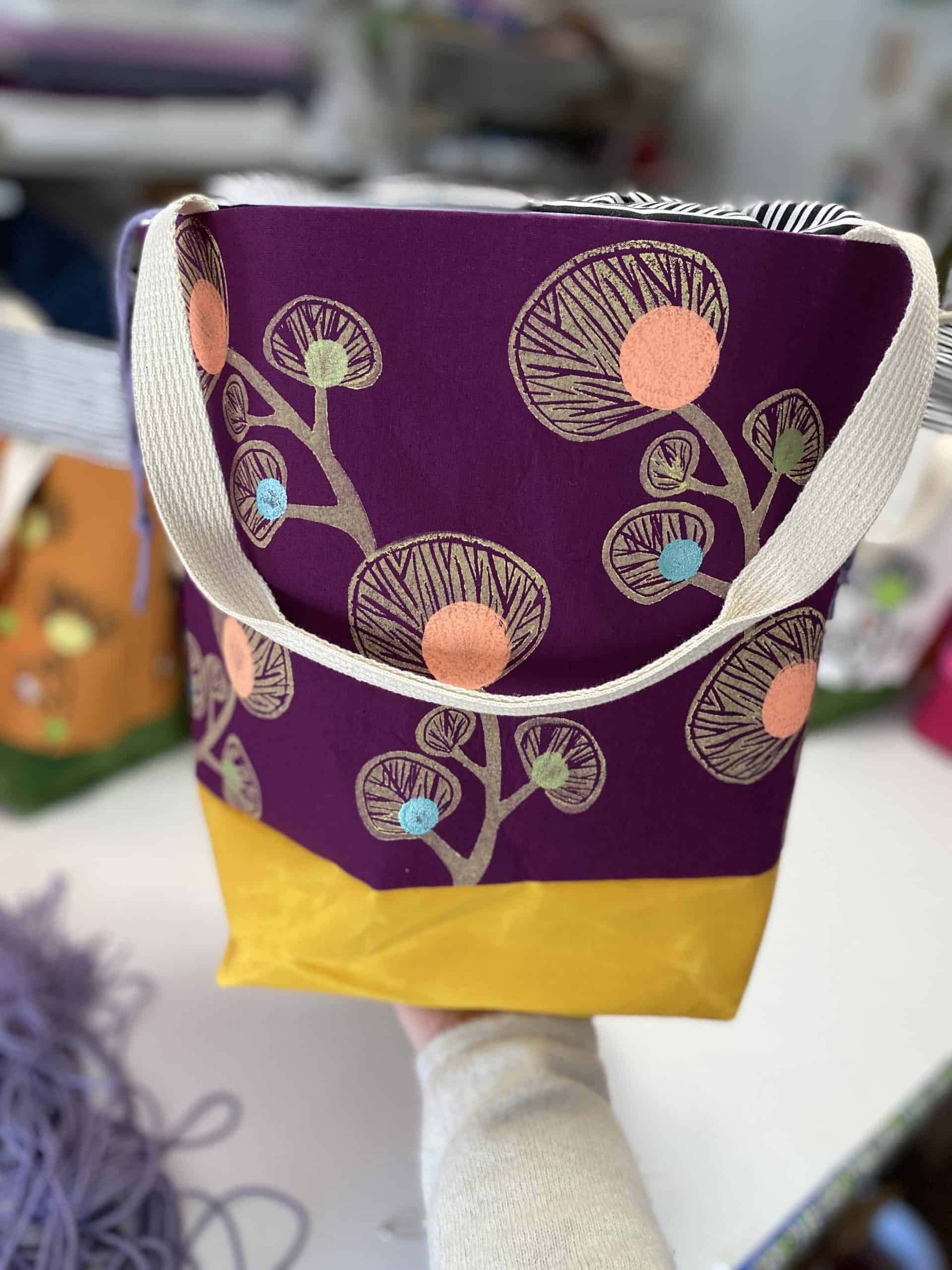A purple, pink and yellow floral tote bag.
