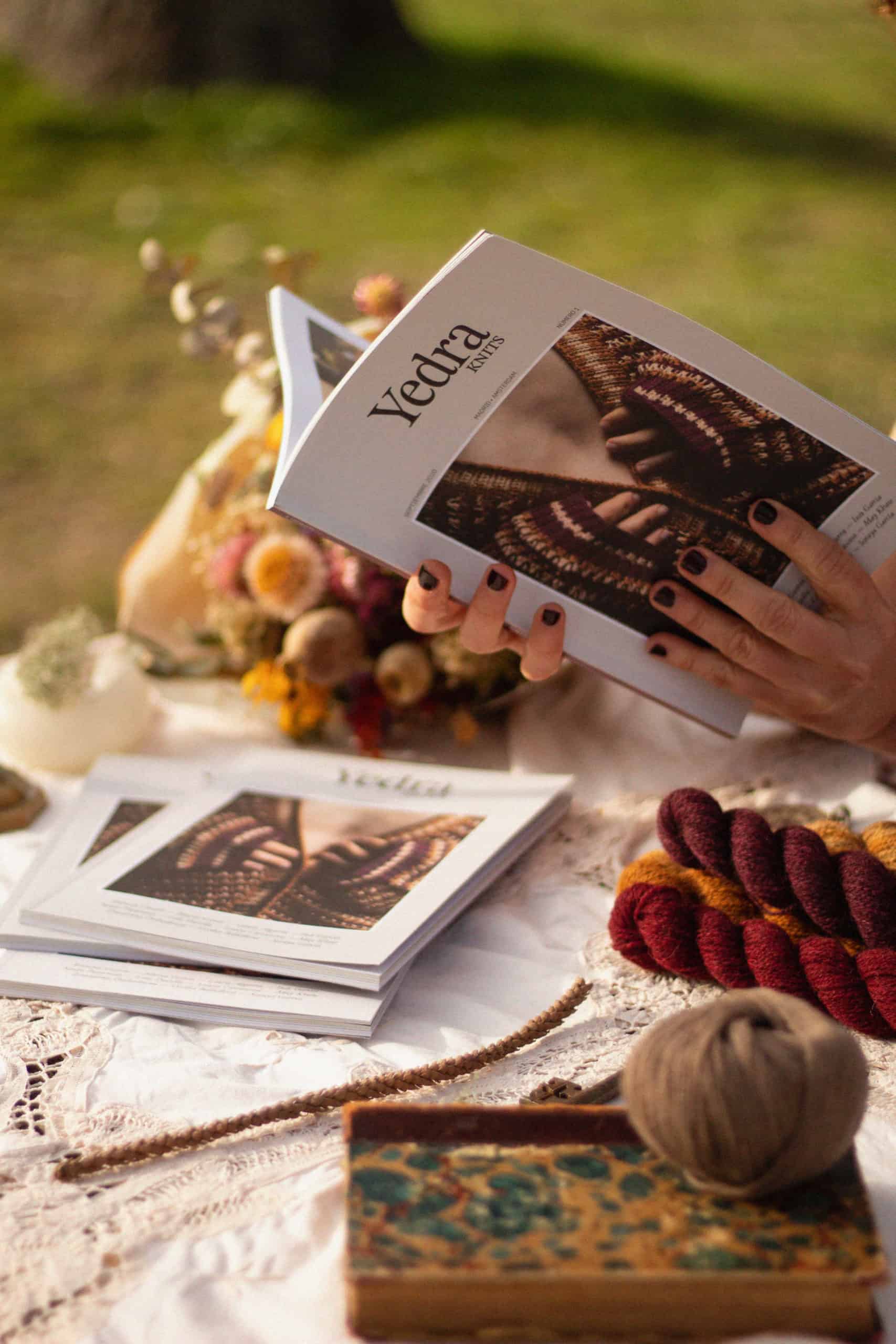 A person hlding open a copy of Yedraknits magazine.