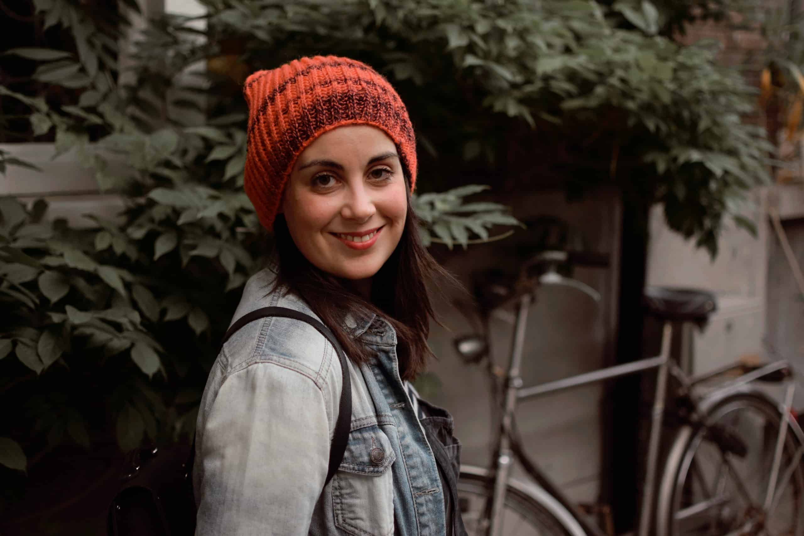 A woman in a red knit beanie smiles at the camera.
