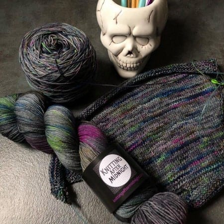 Gray yarn with green and pink speckles next to a skull. 