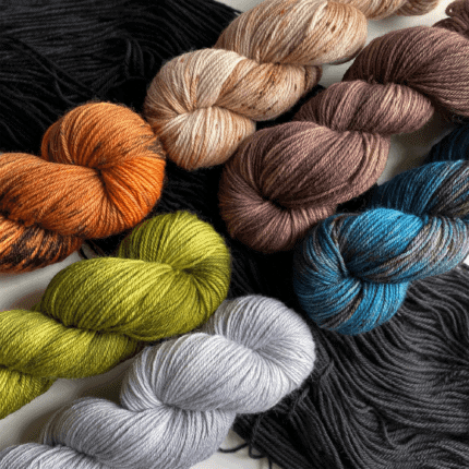 Skeins of orange, green, gray, peach, brown and blue and gray yarn.