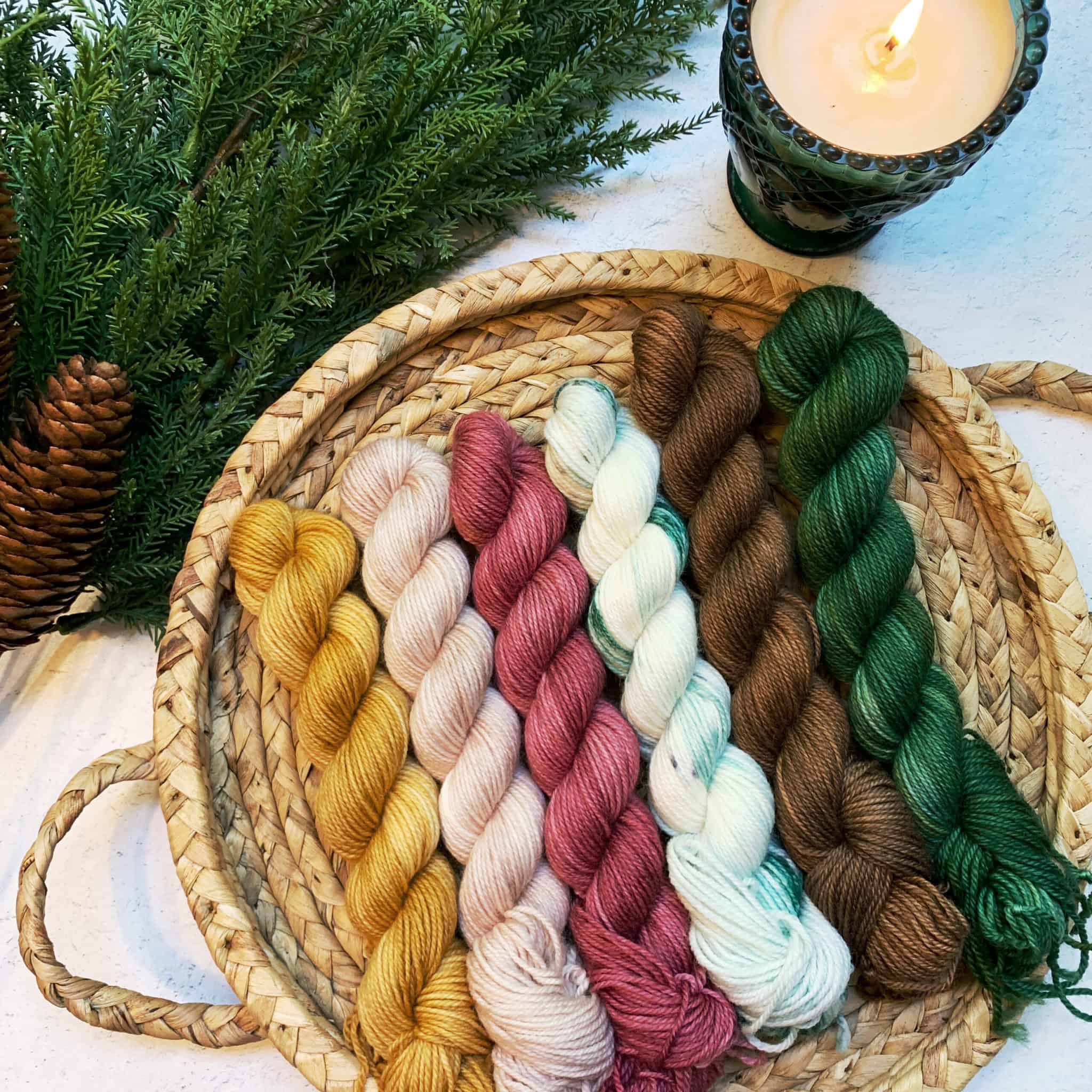 Gold, pink, red, white, brown and green yarn in a flat basket.