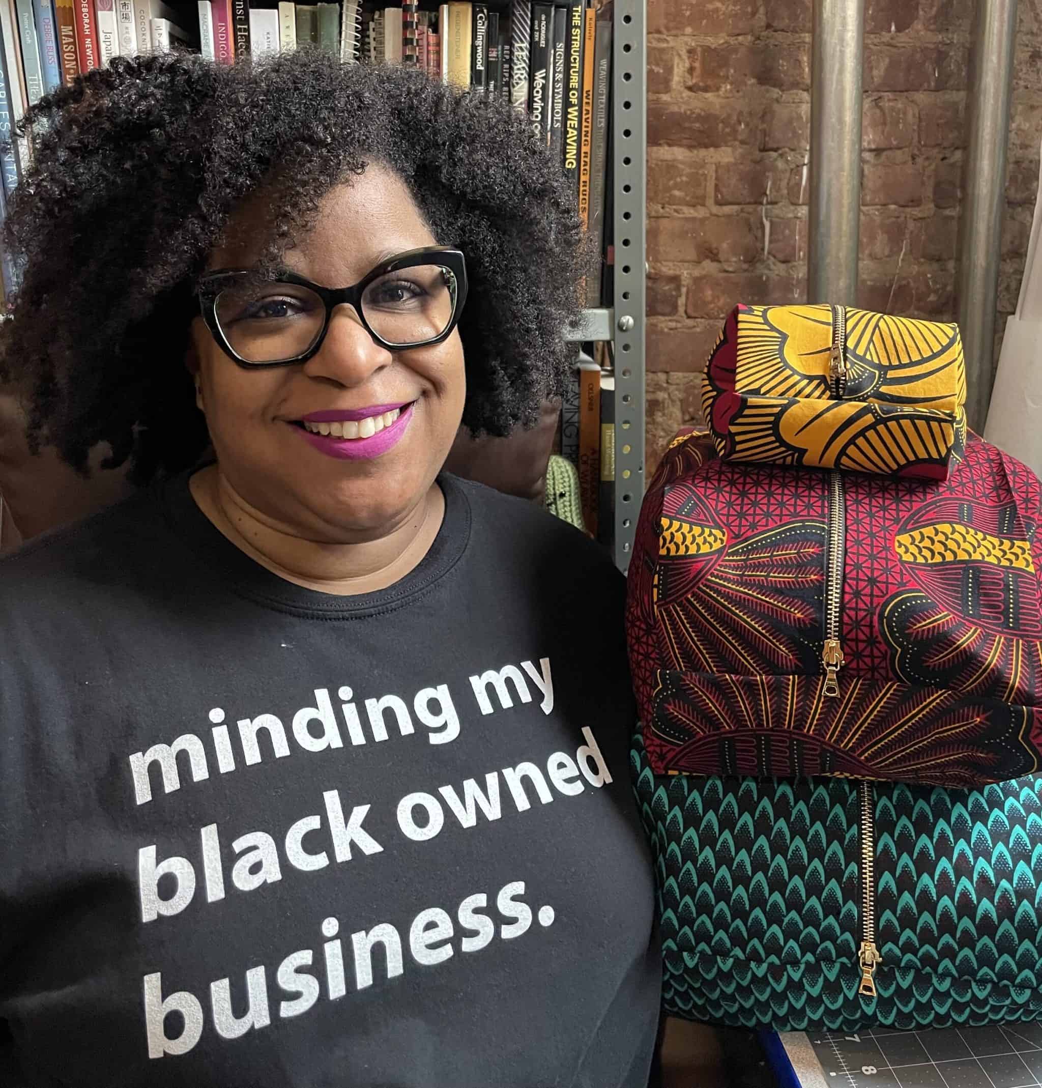 A black woman wears a T-shirt that reads minding my black owned business.