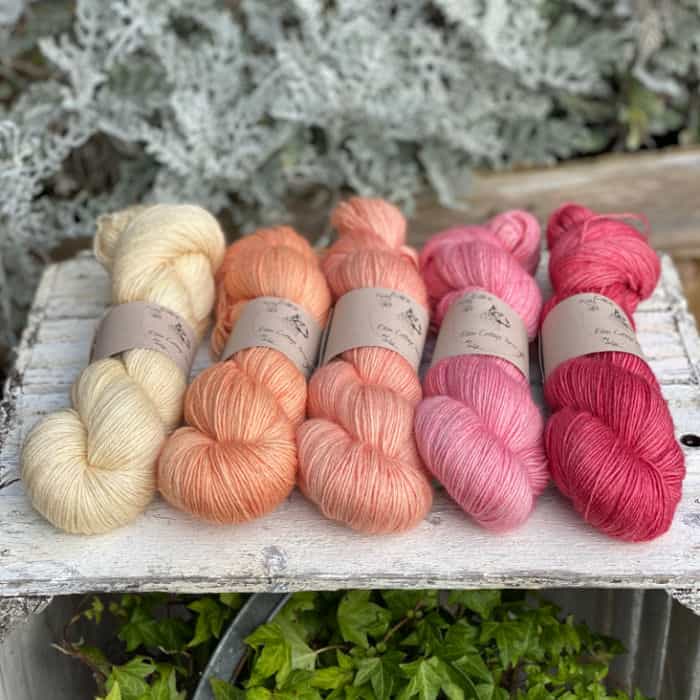 Skeins of yellow, peach and pink yarn in a row.