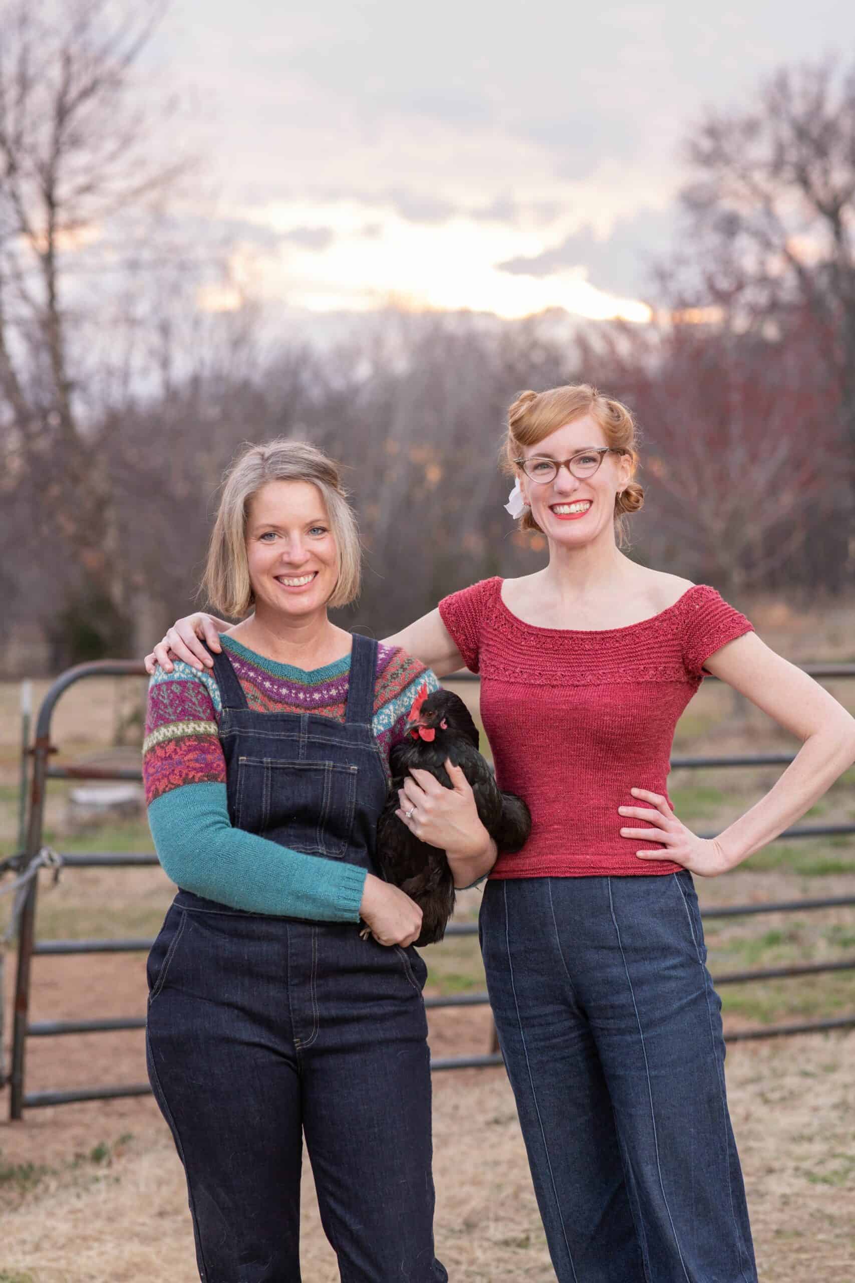 Two women standing in a field. They are wearing hand-knit sweaters.