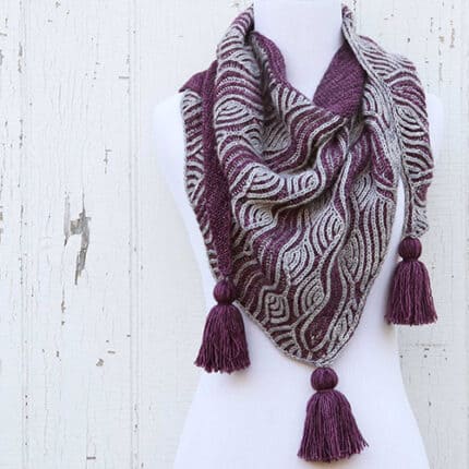 A purple and gray brioche shawl with tassels.