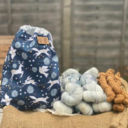 A blue drawstring bag with animals and skeins of blue and gold yarn.