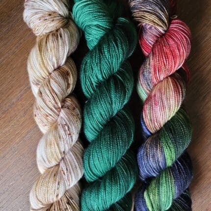 Skeins of white speckled, teal and pink, purple and green variegated hand-dyed yarn.