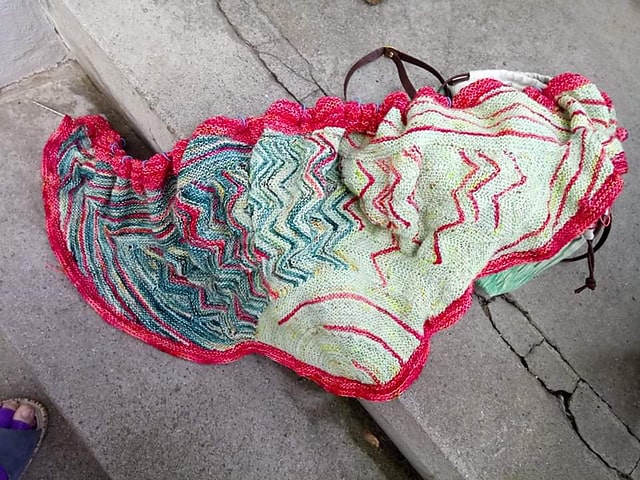 A green and red patterned shawl with a red edging.