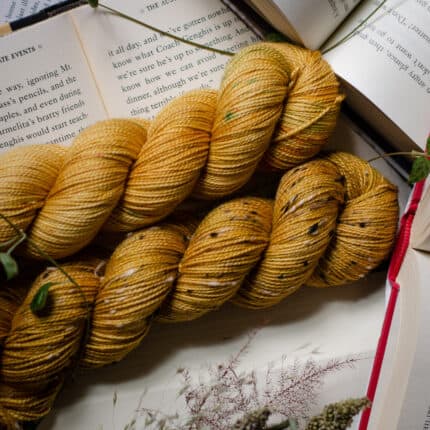 Two skeins of warm gold yarn resting on open books.