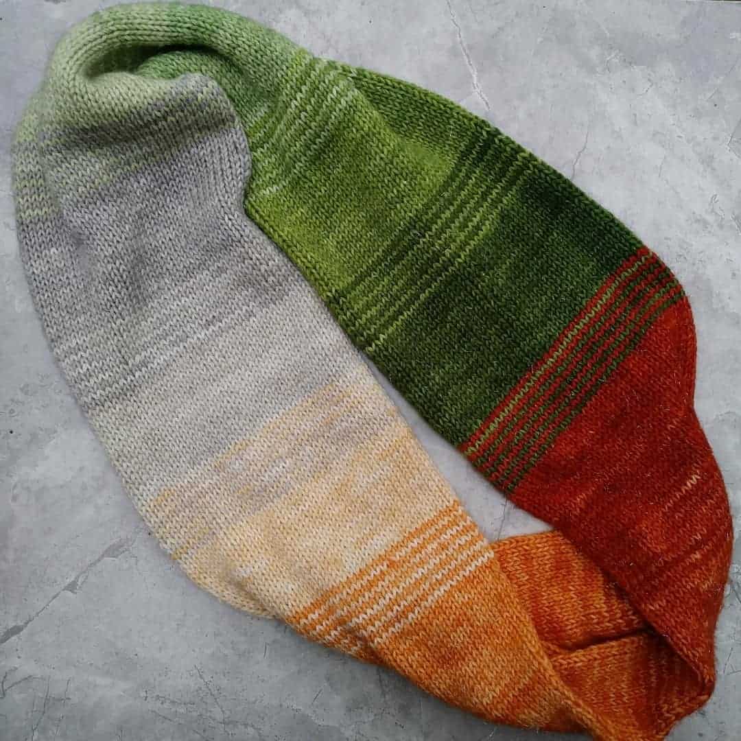 A green, brown, orange, tan and gray striped knit infinity scarf.