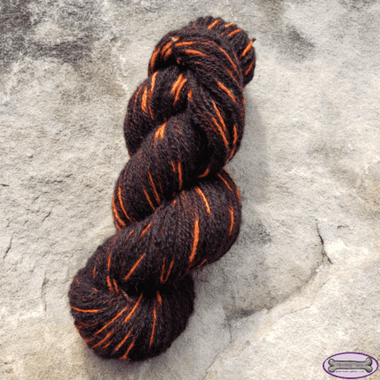 A skein of black yarn with orange sequences.