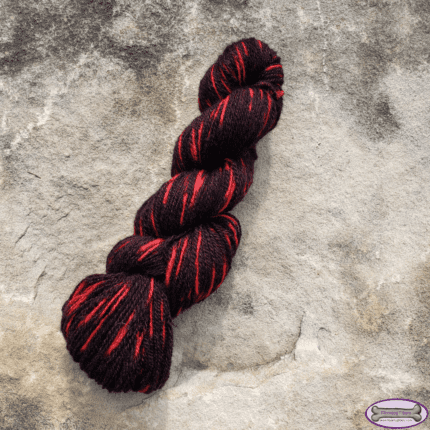 A skein of black yarn with red sequences.